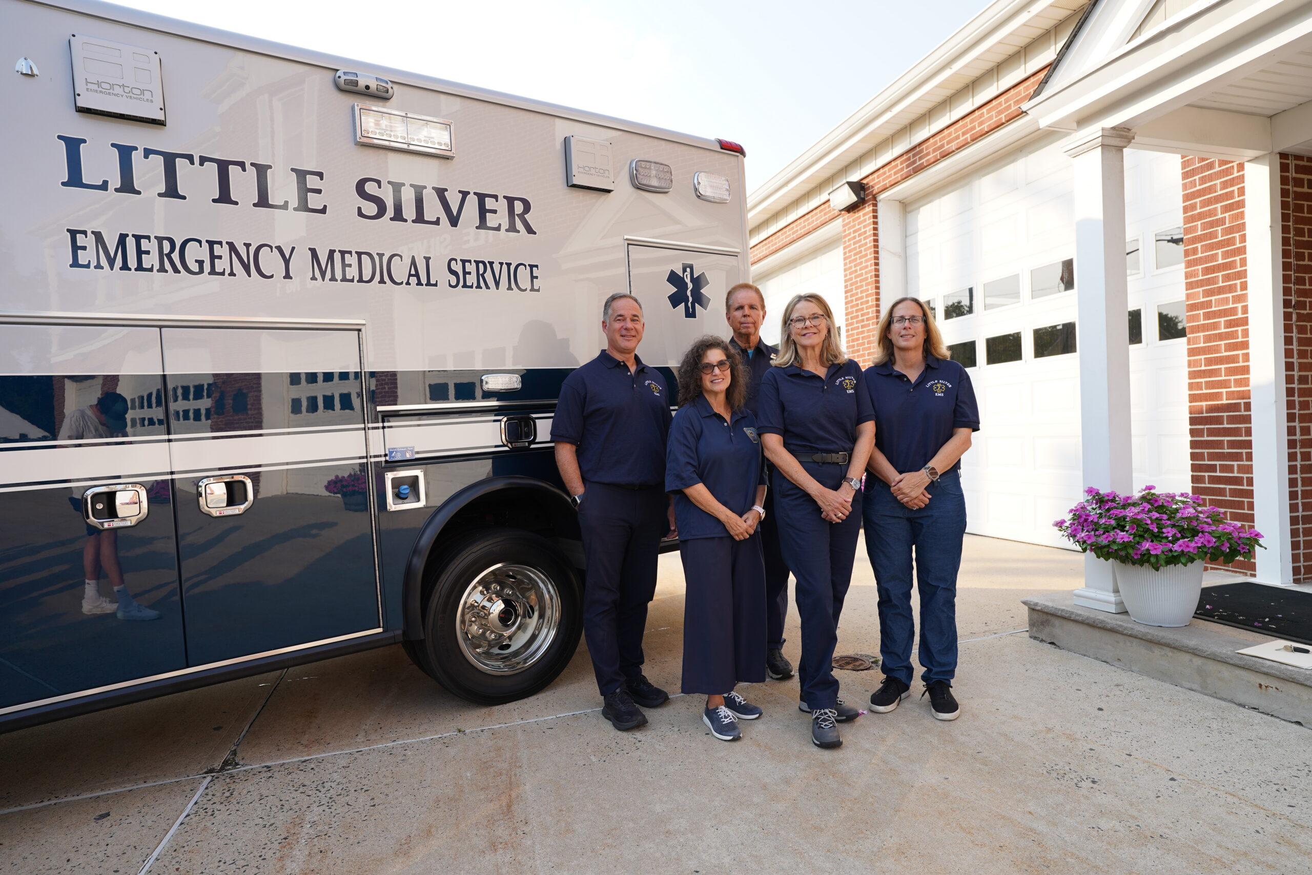 Little Silver EMS volunteers posing for a photo in front of an ambulance.
